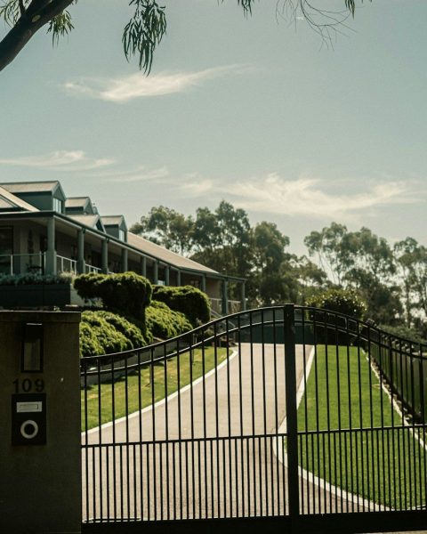 a gated driveway with a house in the background