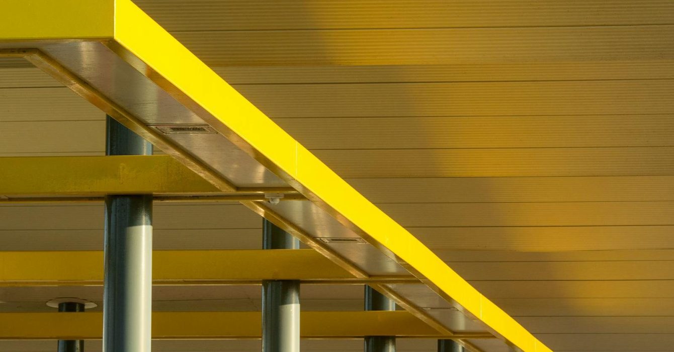 Artistic low-angle view of modern yellow structural beams against a ceiling.