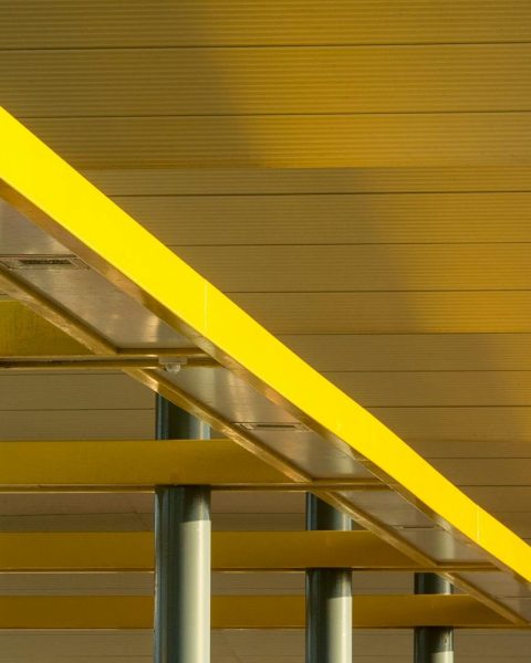 Artistic low-angle view of modern yellow structural beams against a ceiling.