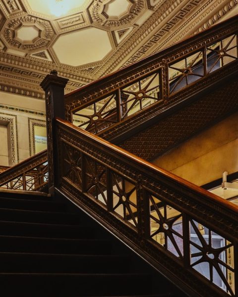 Wooden staircase ascends towards a patterned ceiling.